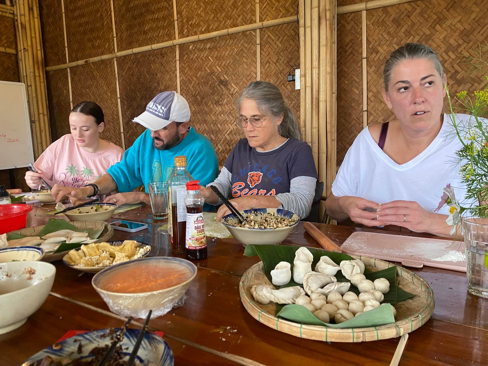 Guests folding dumplings by hand, with a tray of fresh dumplings